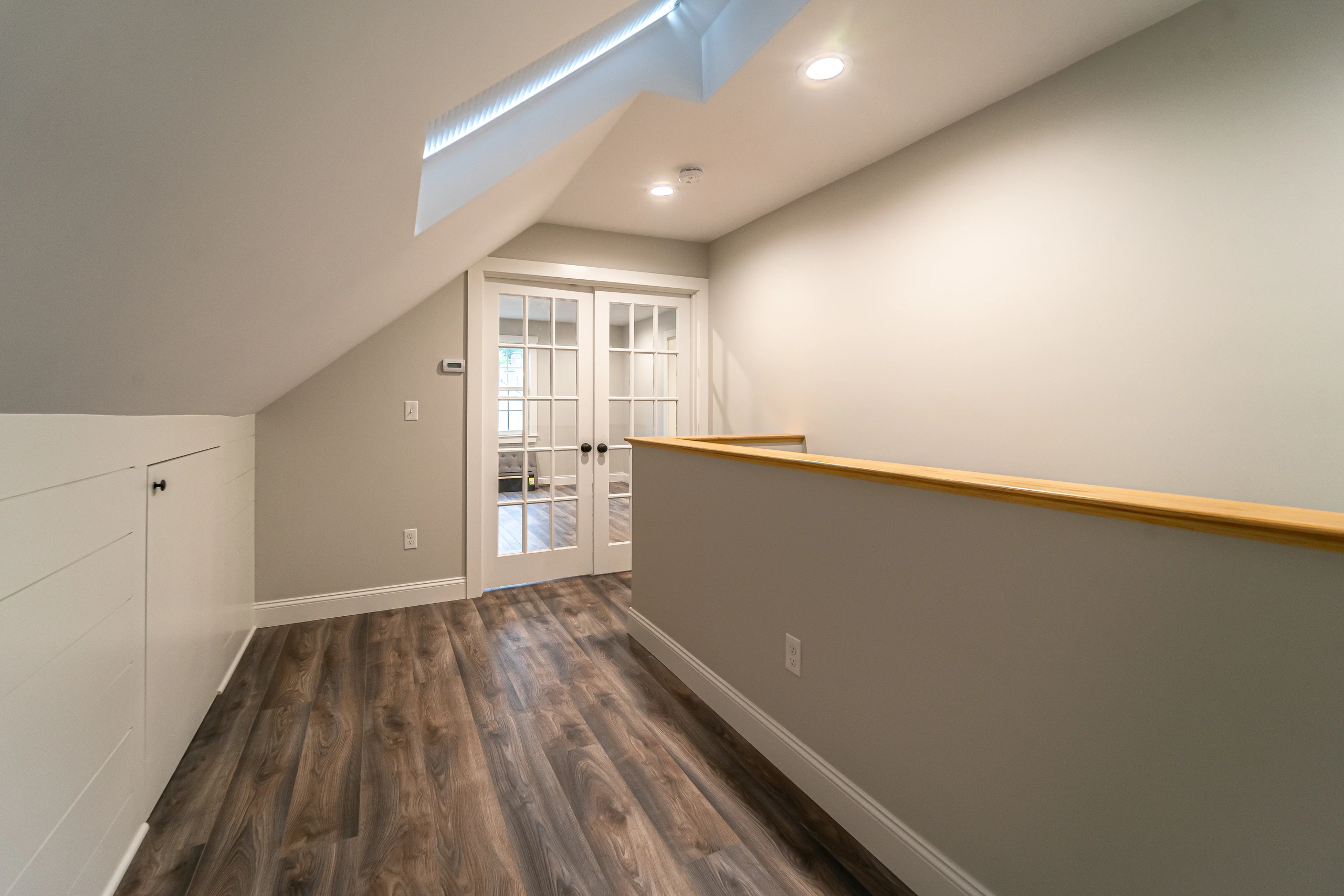 Landing leading to French doors with shiplap knee wall and storage access door, attic conversion in Framingham, MA