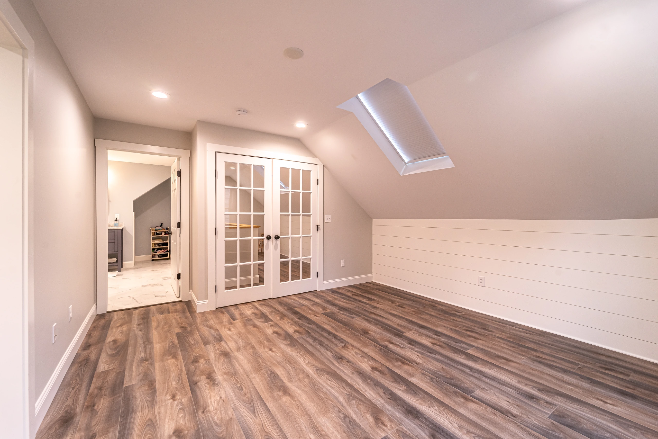 Attic room with skylight, French doors, and view into the new bathroom, attic conversion in Framingham, MA