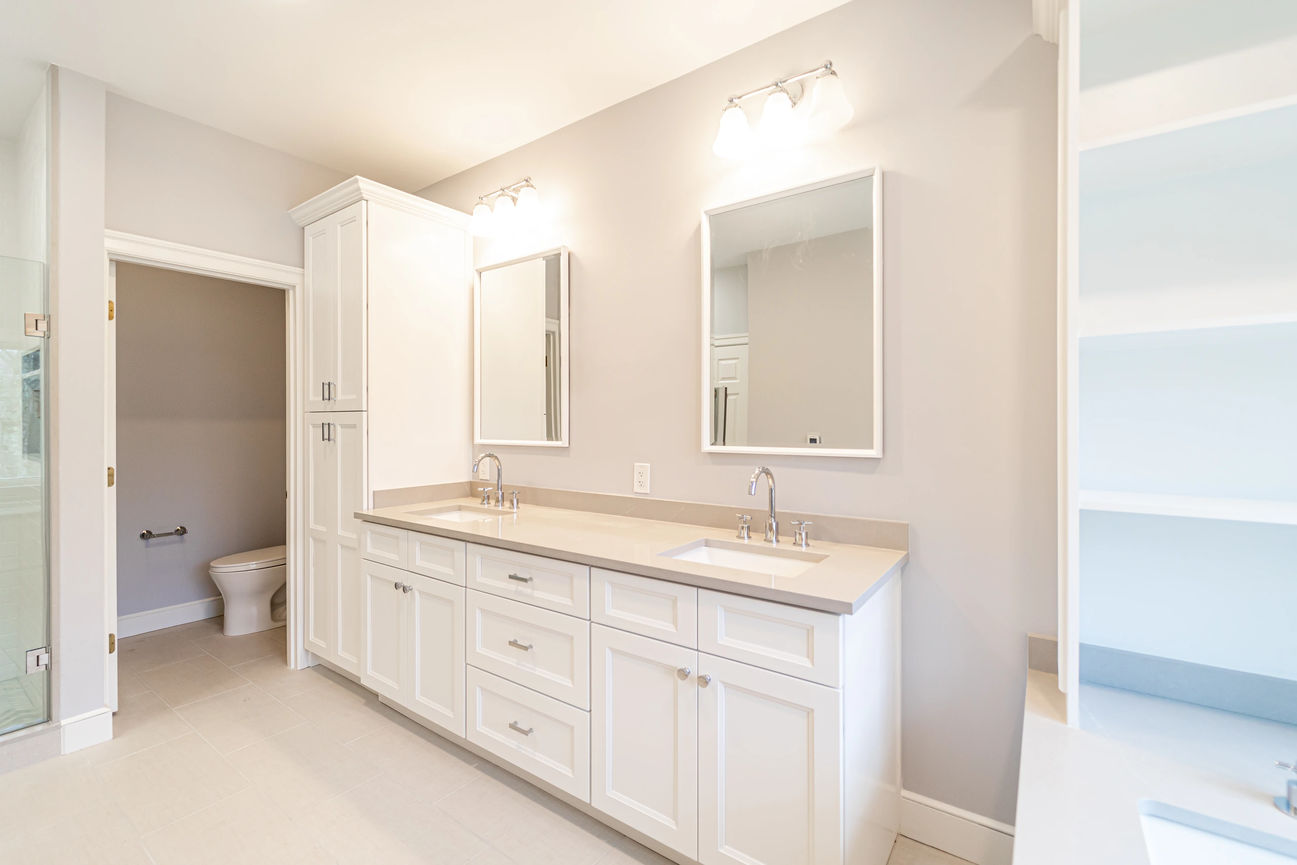 Finished bathroom remodel in Sherborn, MA, with white double vanity, linen tower, and private toilet room