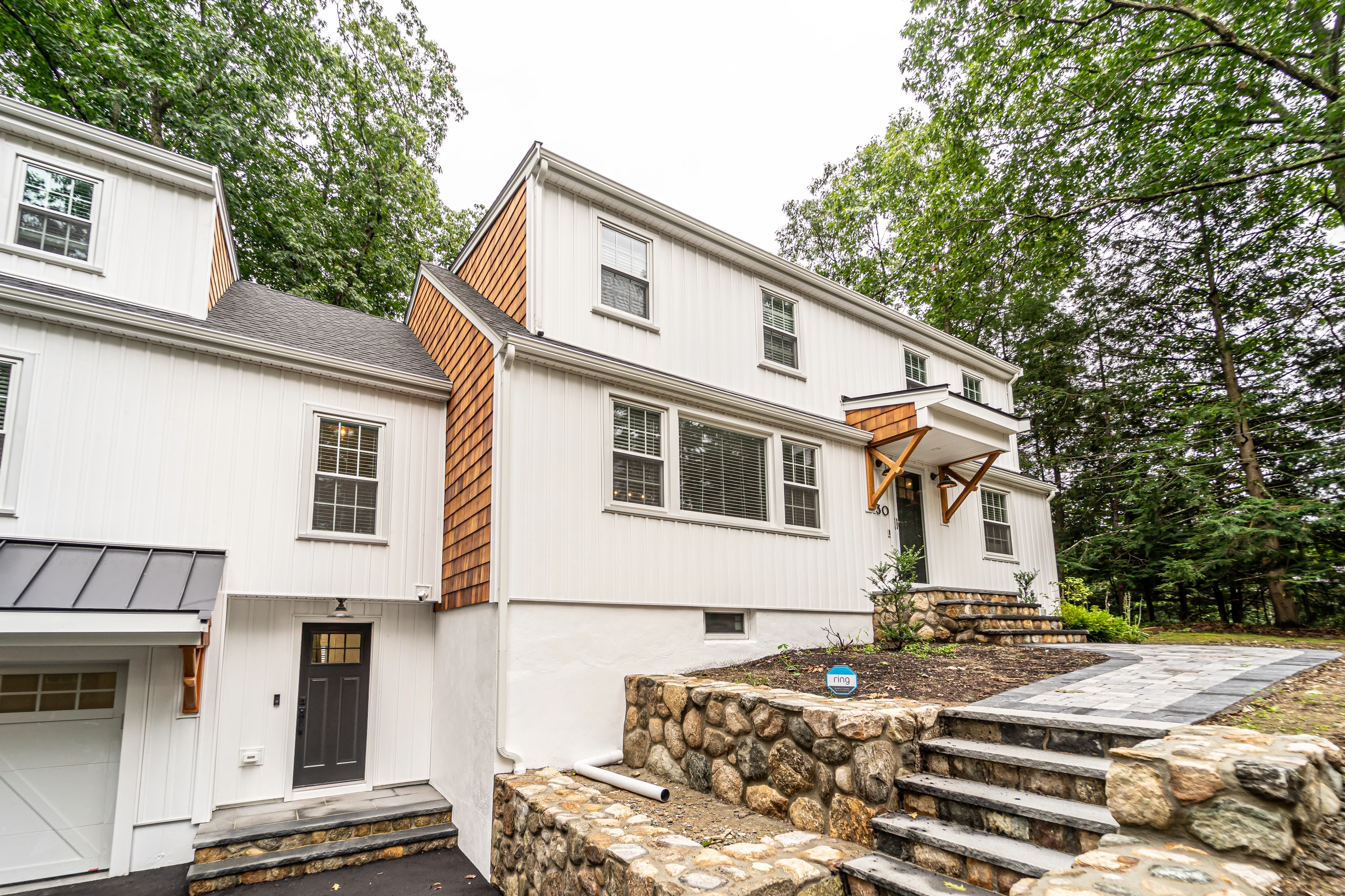 Front corner after the addition, with cedar shingle accent, new entry canopy, and fieldstone steps, home addition in Natick, MA