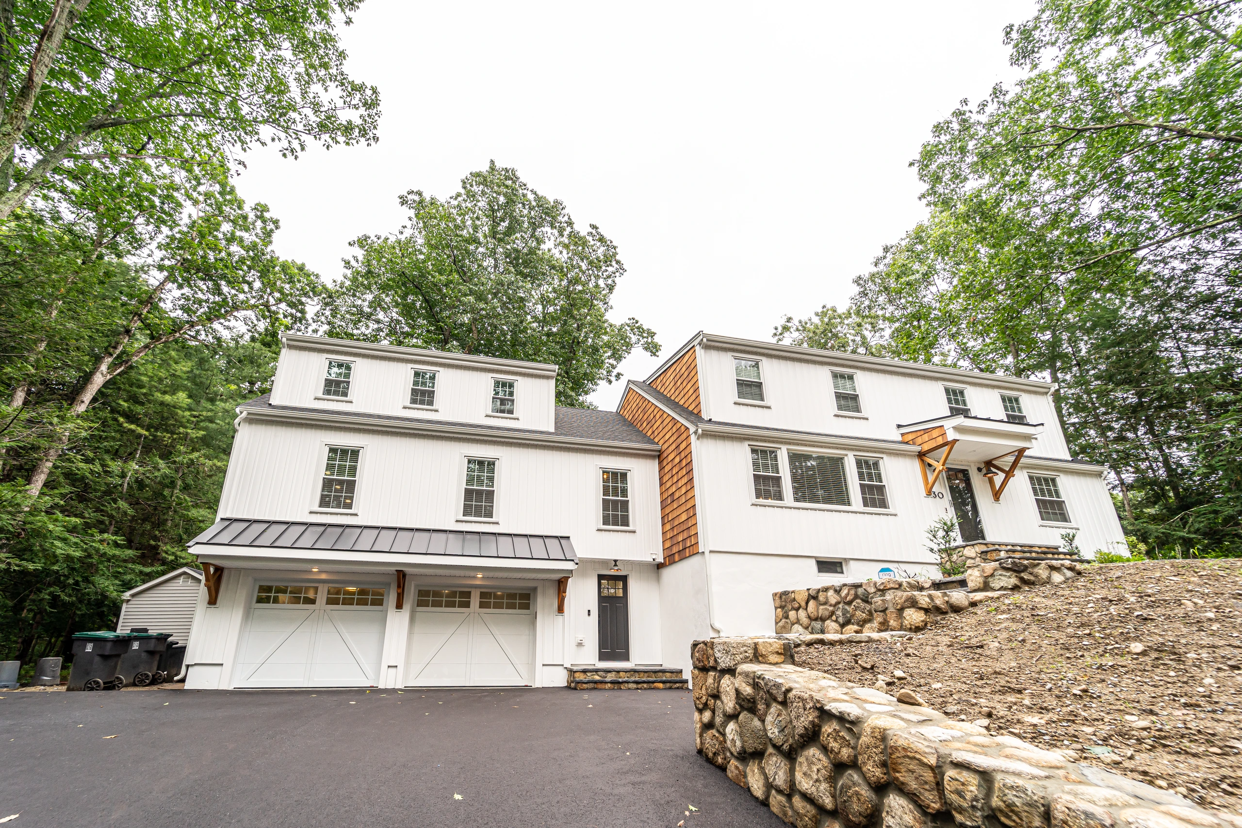 Finished addition with two-car garage, metal roof accent, and fieldstone retaining wall, home addition in Natick, MA
