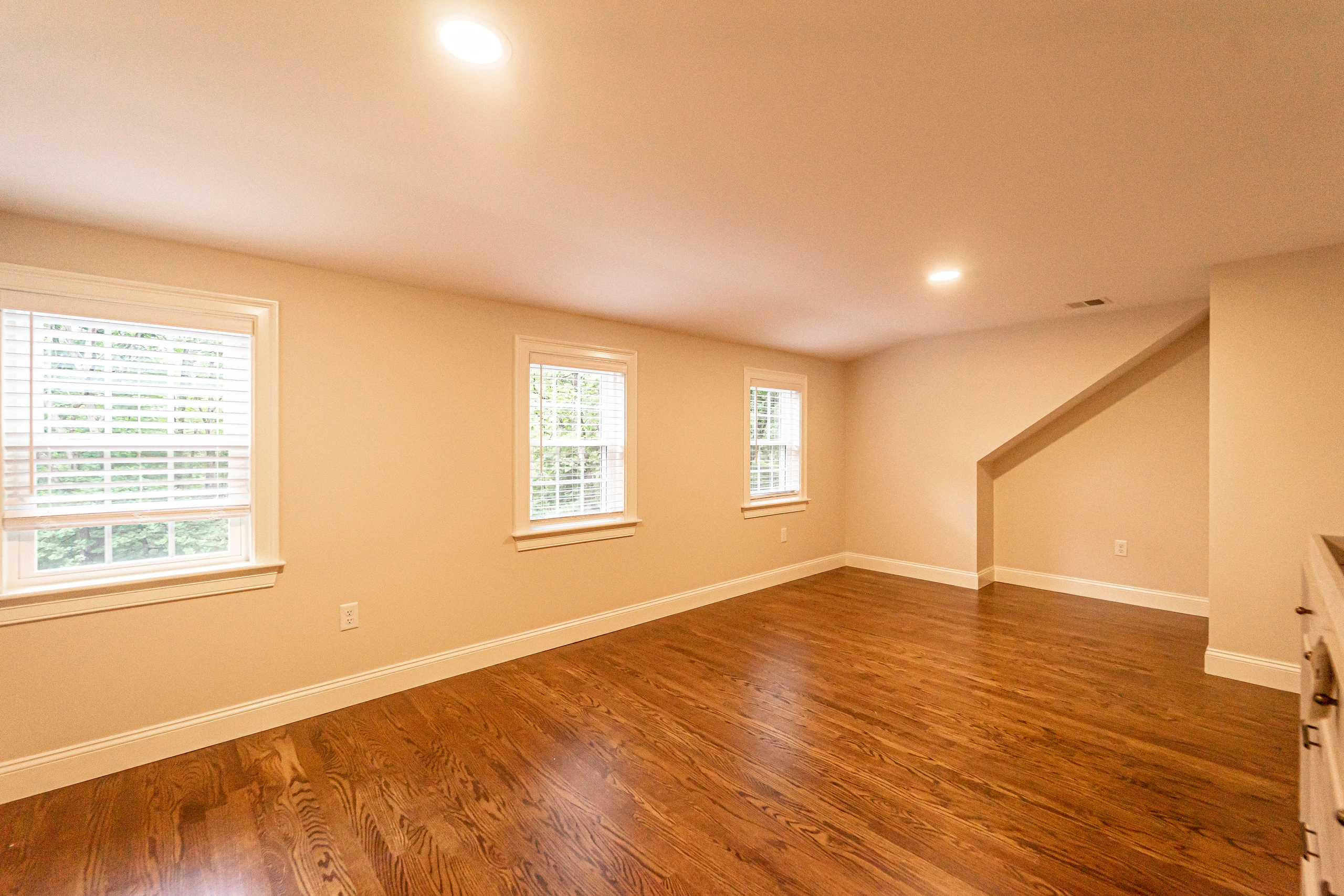 Finished bedroom with hardwood floor, three windows, and recessed lighting, home addition in Natick, MA