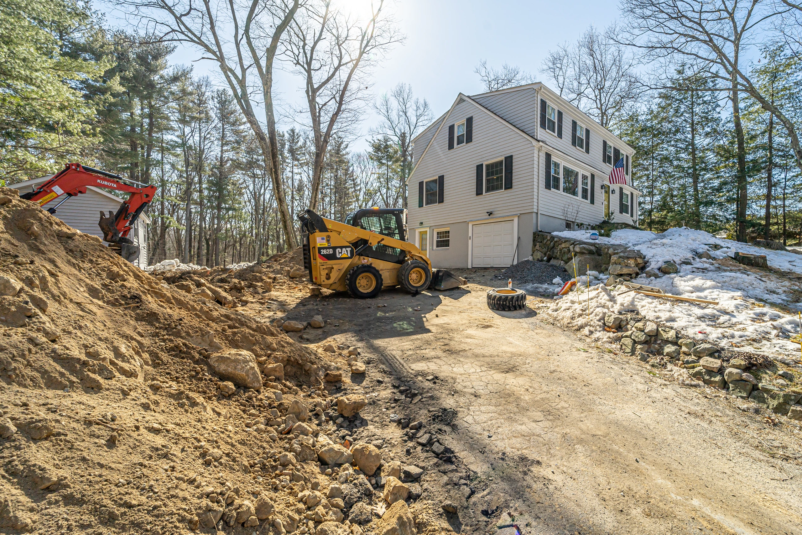 Original house and single garage door with excavation equipment on site, home addition in Natick, MA