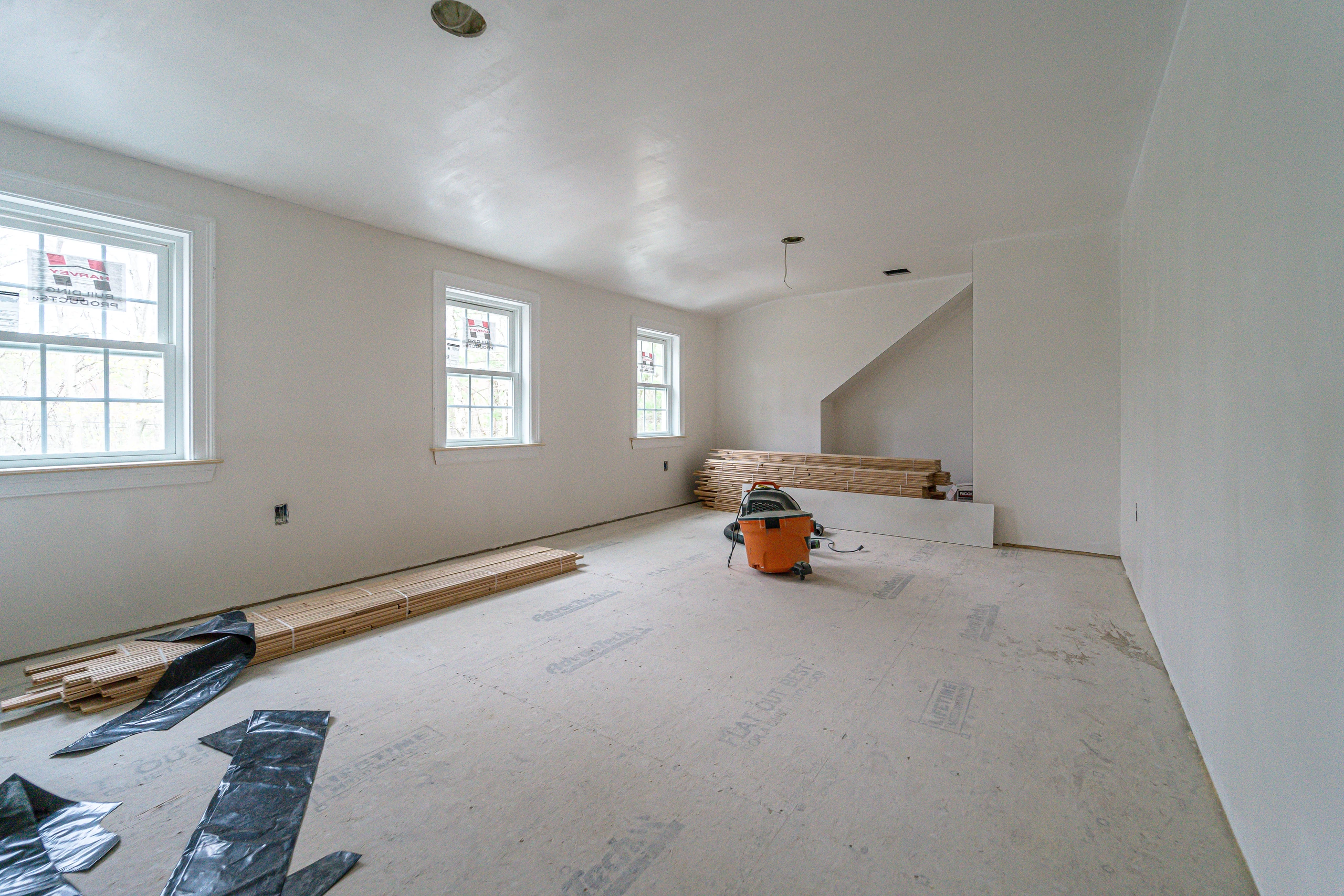New bedroom at drywall stage with subfloor and three windows, home addition in Natick, MA